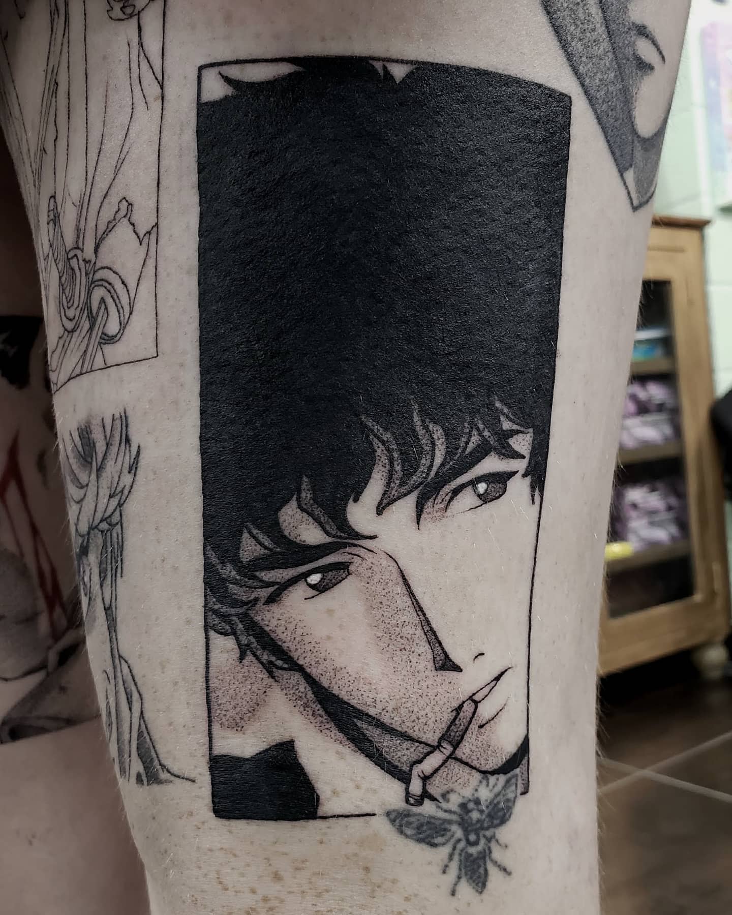 Tattoo of Spike Spiegel from Cowboy Bebop, in a close-up portrait style, smoking a cigarette within a rectangular frame